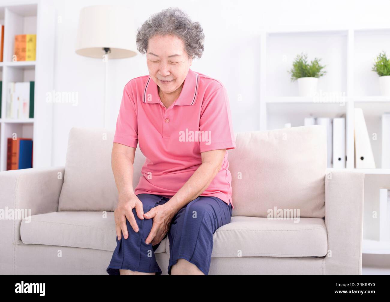 Asian senior woman sitting on sofa and having the joint pain Stock Photo