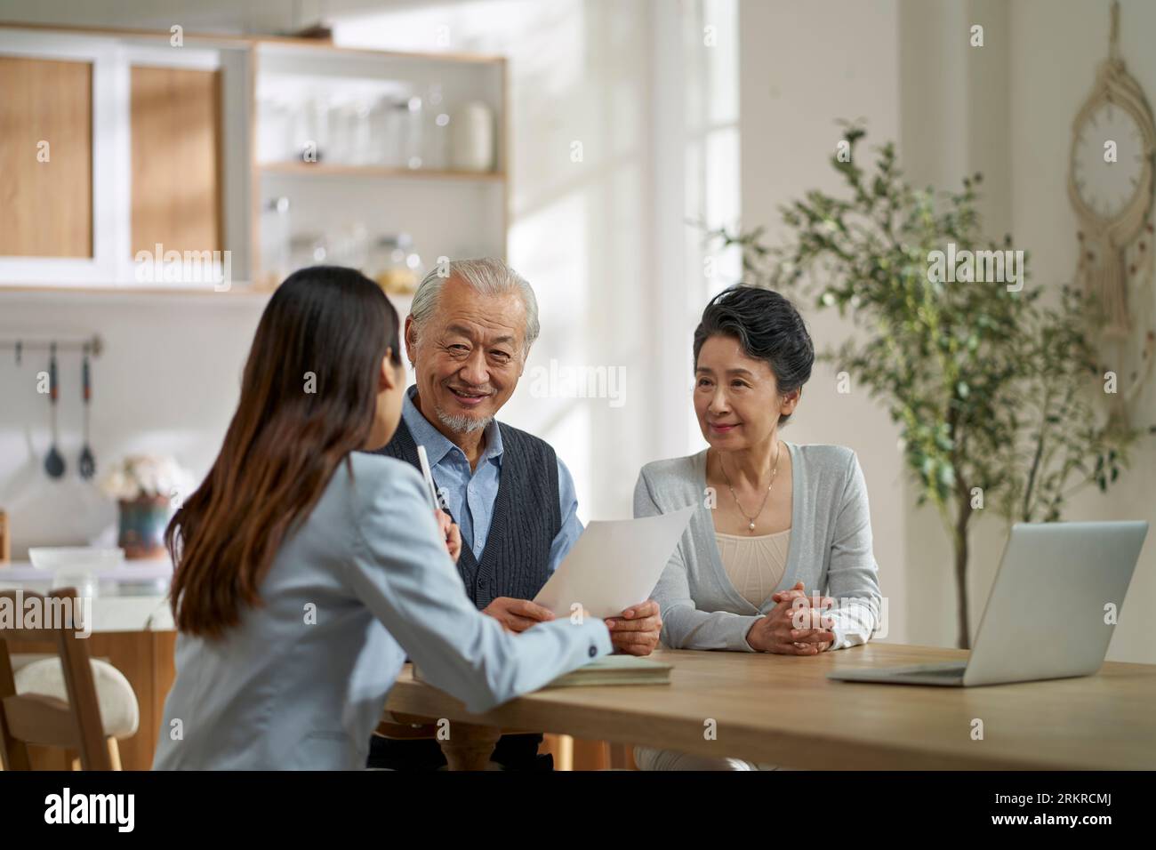 young asian door to door saleswoman selling product or service to a senior couple Stock Photo