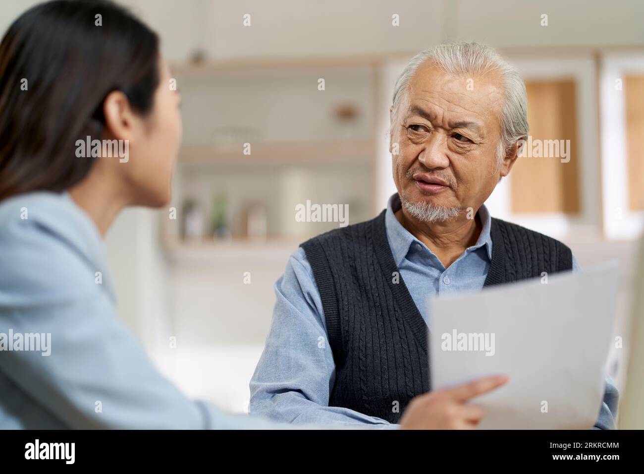 senior asian man appears to be confused by and suspicious at a sales person selling financial product Stock Photo