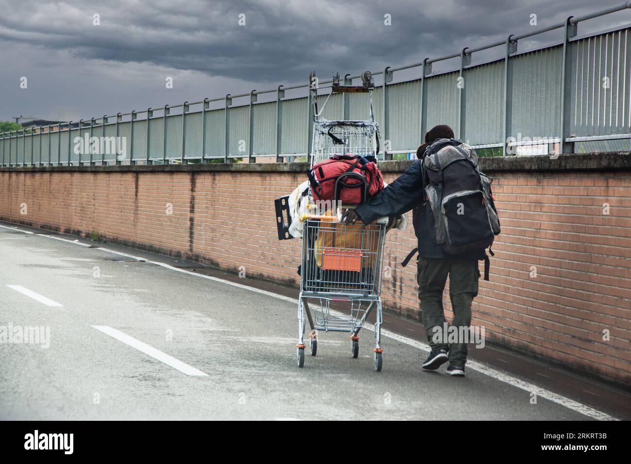 homeless pushes shopping cart in the street Stock Photo