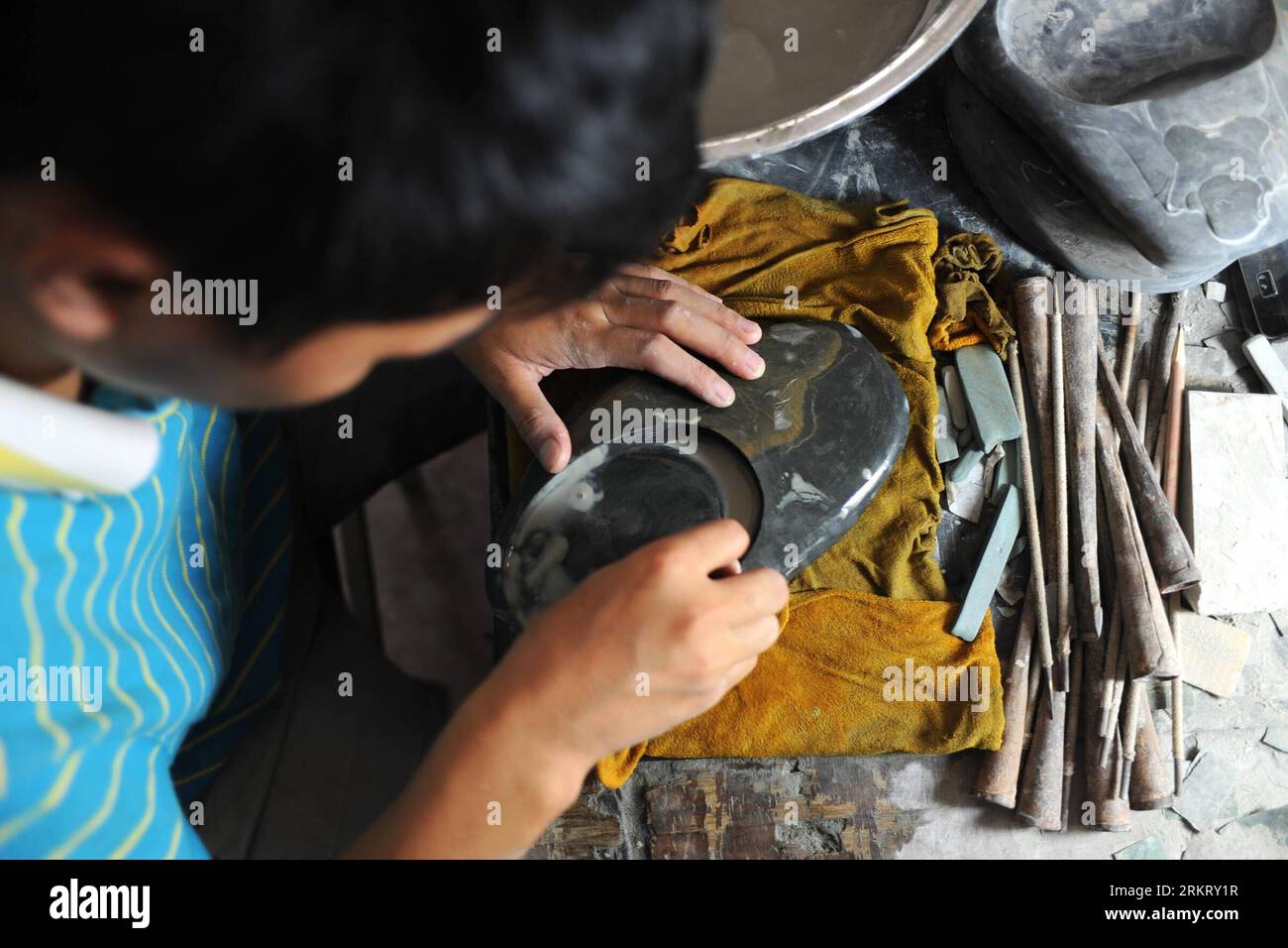Bildnummer: 58328555  Datum: 07.08.2012  Copyright: imago/Xinhua (120809) -- SHEXIAN, Aug. 9, 2012 (Xinhua) -- An apprentice of Wen Xin polishes an inkstone in Shexian County of east China s Anhui Province, Aug. 7, 2012. Wen Xin, a 32-year-old man, is a master of inkstone carving in Shexian of Anhui Province. He started to learn the craftsmanship during his teenage years under the influence of his family. After years of study as research, Wen Xin developed a series of skills and patterns in carving the inkstone. The themes of his inkstones, various from landscapes, portrait, flowers to creatur Stock Photo