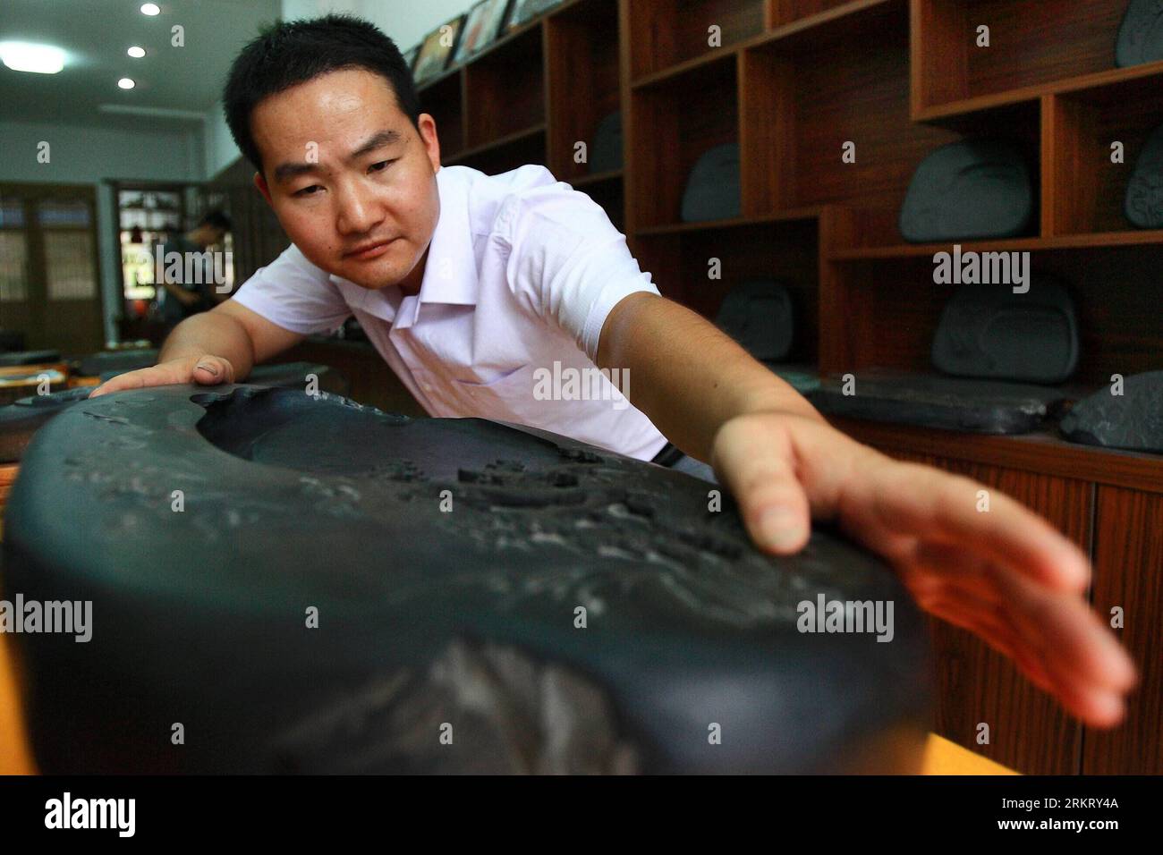 Bildnummer: 58328552  Datum: 07.08.2012  Copyright: imago/Xinhua (120809) -- SHEXIAN, Aug. 9, 2012 (Xinhua) -- Wen Xin examines an inkstone carving in the showroom in Shexian County of east China s Anhui Province, Aug. 7, 2012. Wen Xin, a 32-year-old man, is a master of inkstone carving in Shexian of Anhui Province. He started to learn the craftsmanship during his teenage years under the influence of his family. After years of study as research, Wen Xin developed a series of skills and patterns in carving the inkstone. The themes of his inkstones, various from landscapes, portrait, flowers to Stock Photo