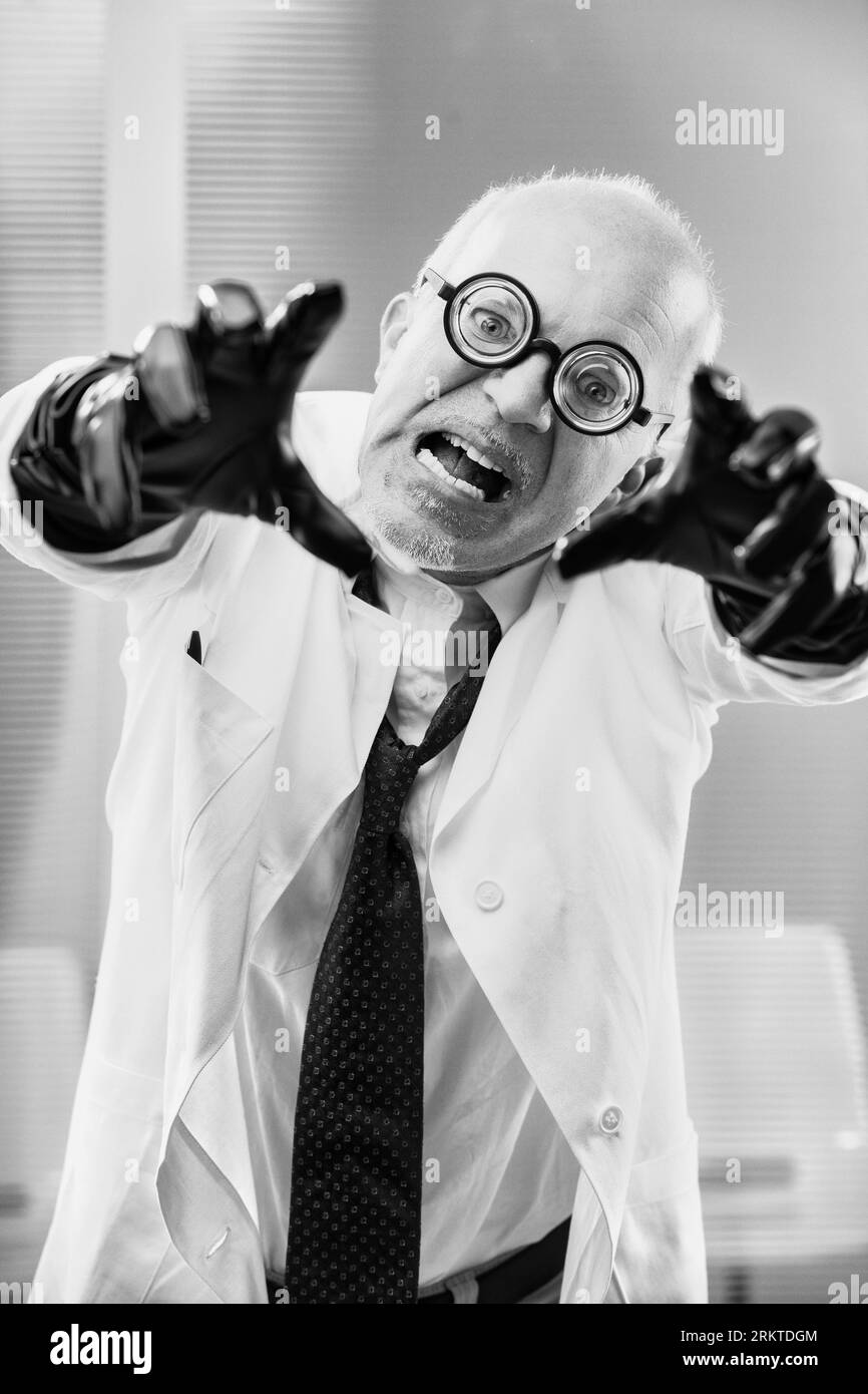 In a monochrome vintage style, an evil genius in a lab coat and black gloves conspires globally, crafting banned toxins, possibly in secret government Stock Photo