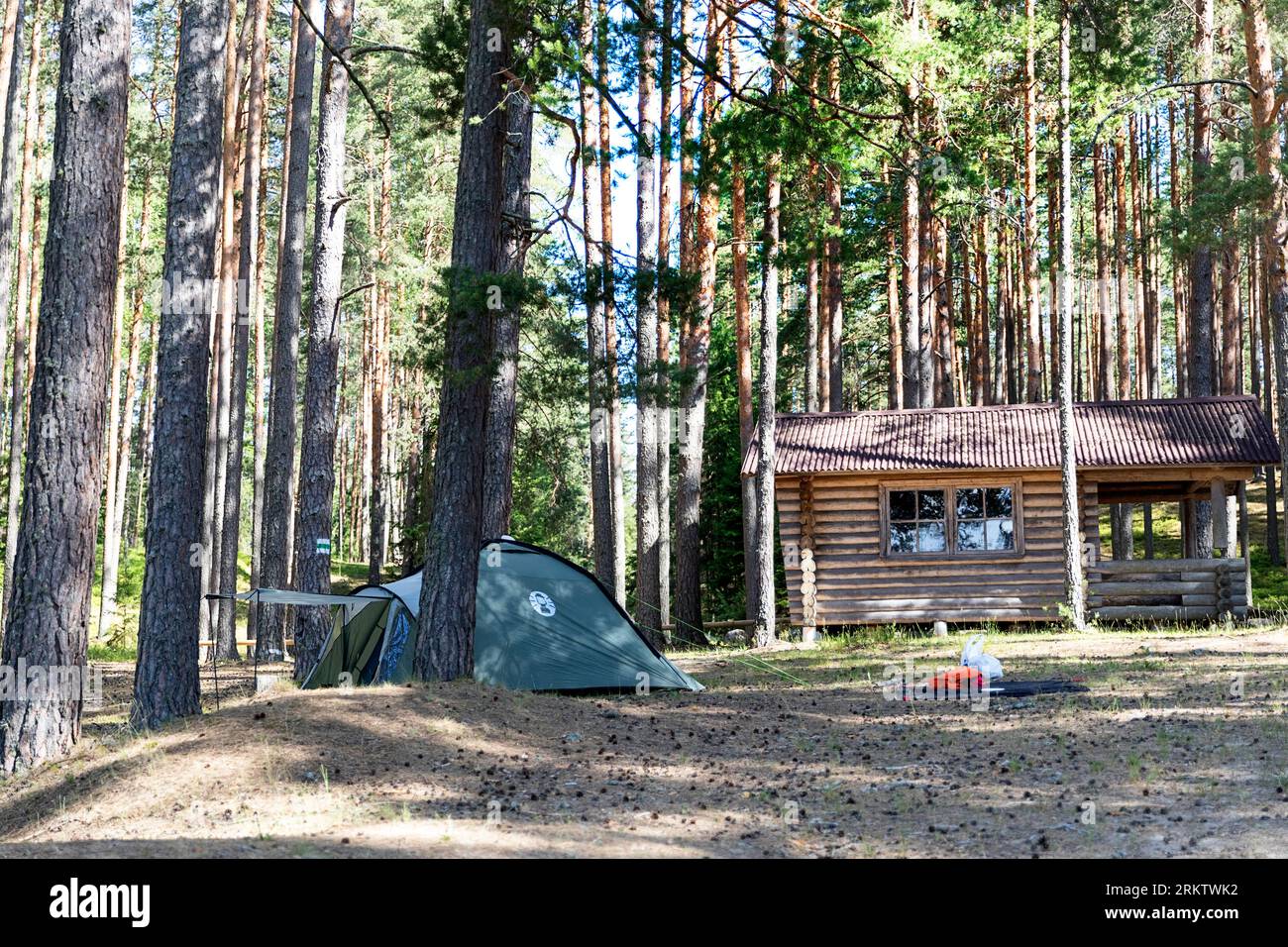 A tent and a cottage in the middle of the pine forest close to the Valgojarv lake in Meenikunno protected area on a sunny summer morning, Estonia Stock Photo