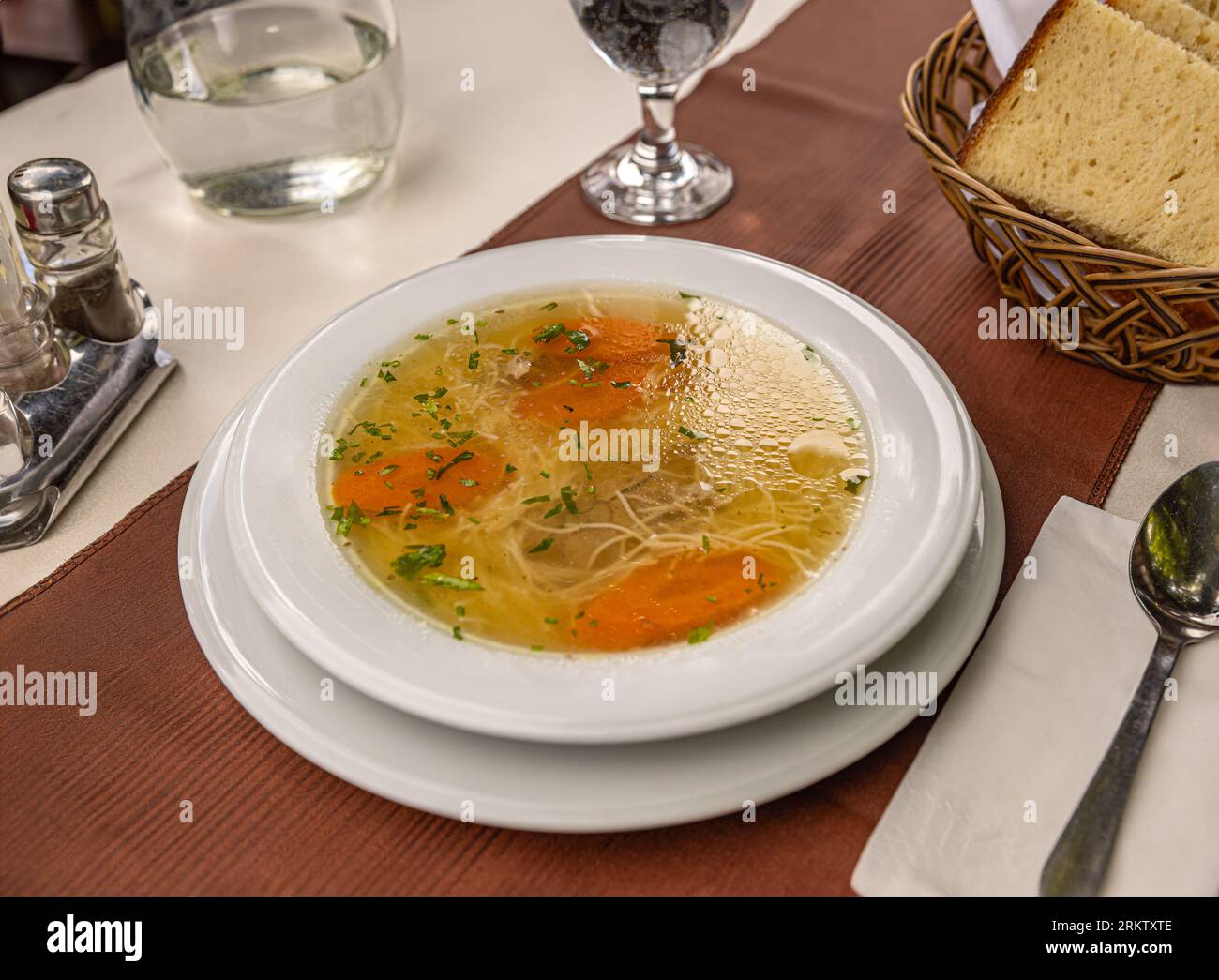 Chicken noodle soup with parsley and vegetables in a white plate Stock