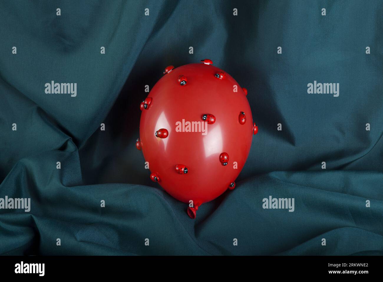 an invasion of numerous ladybugs on a red inflatable balloon with a ...
