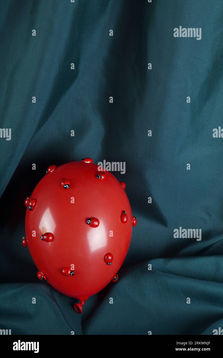 an invasion of numerous ladybugs on a red inflatable balloon with a ...