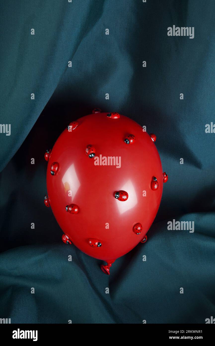 an invasion of numerous ladybugs on a red inflatable balloon with a ...