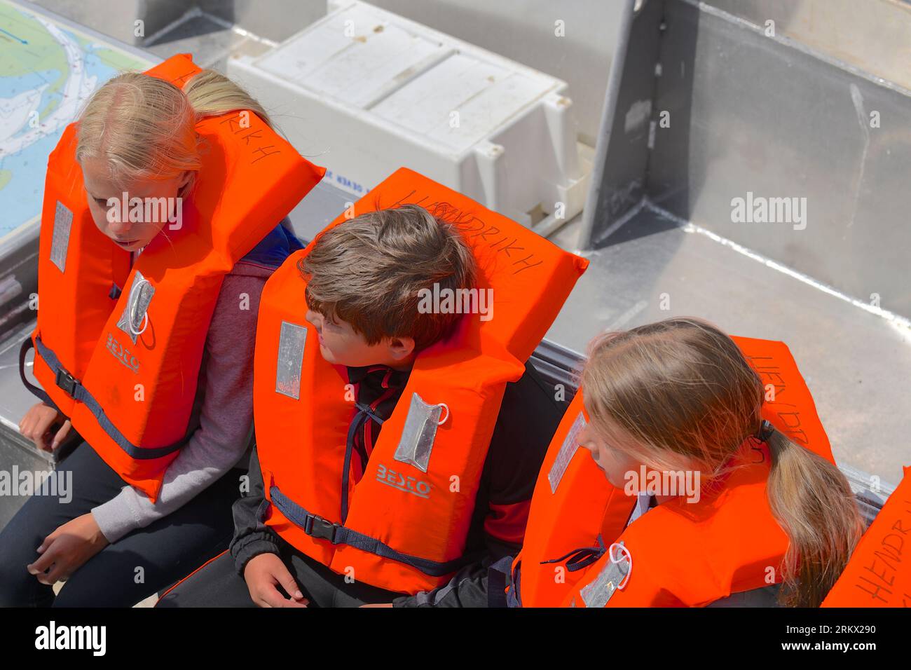 Three children wear a life jacket during a boat trip somewhere in