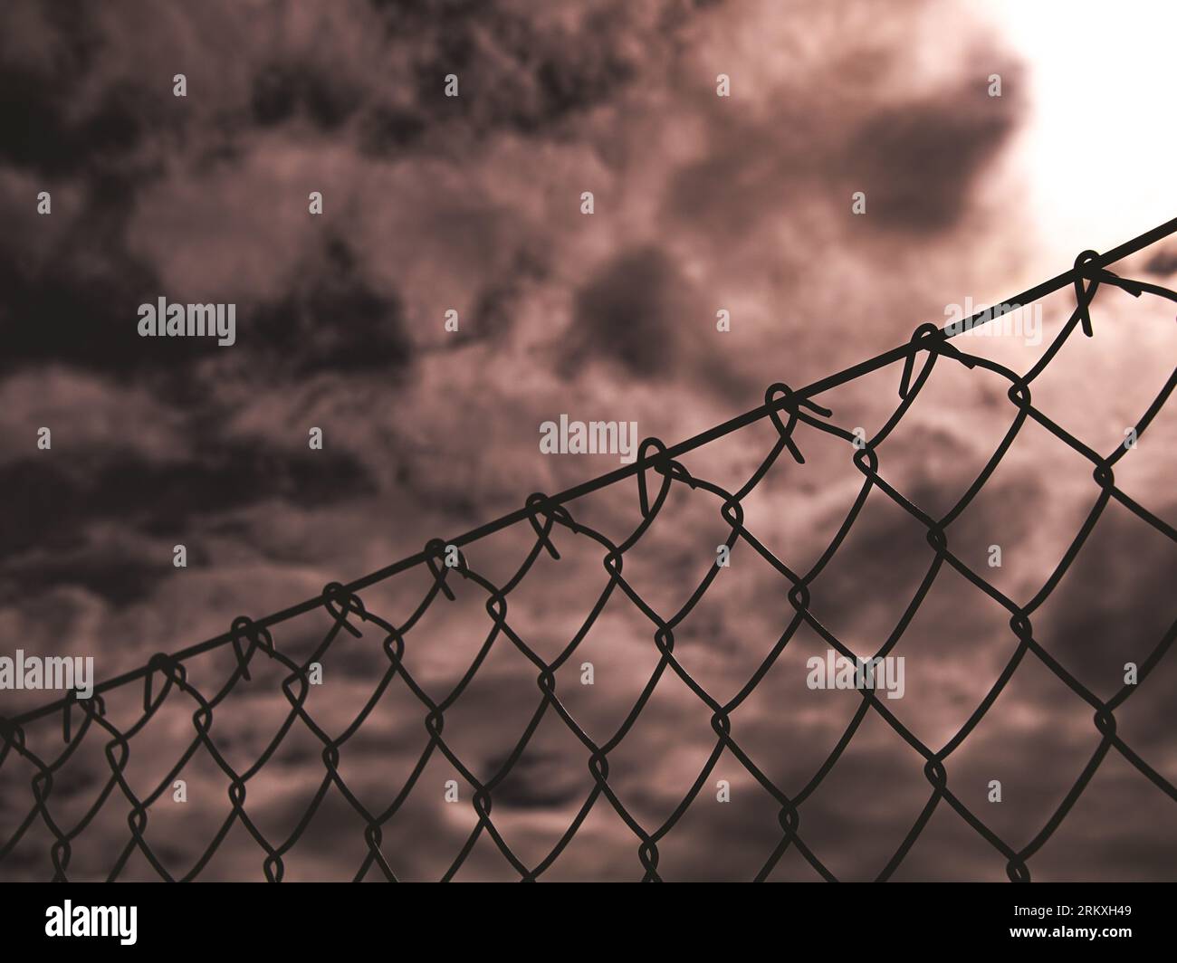 Low angle view of chainlink fence against cloudy sky Stock Photo