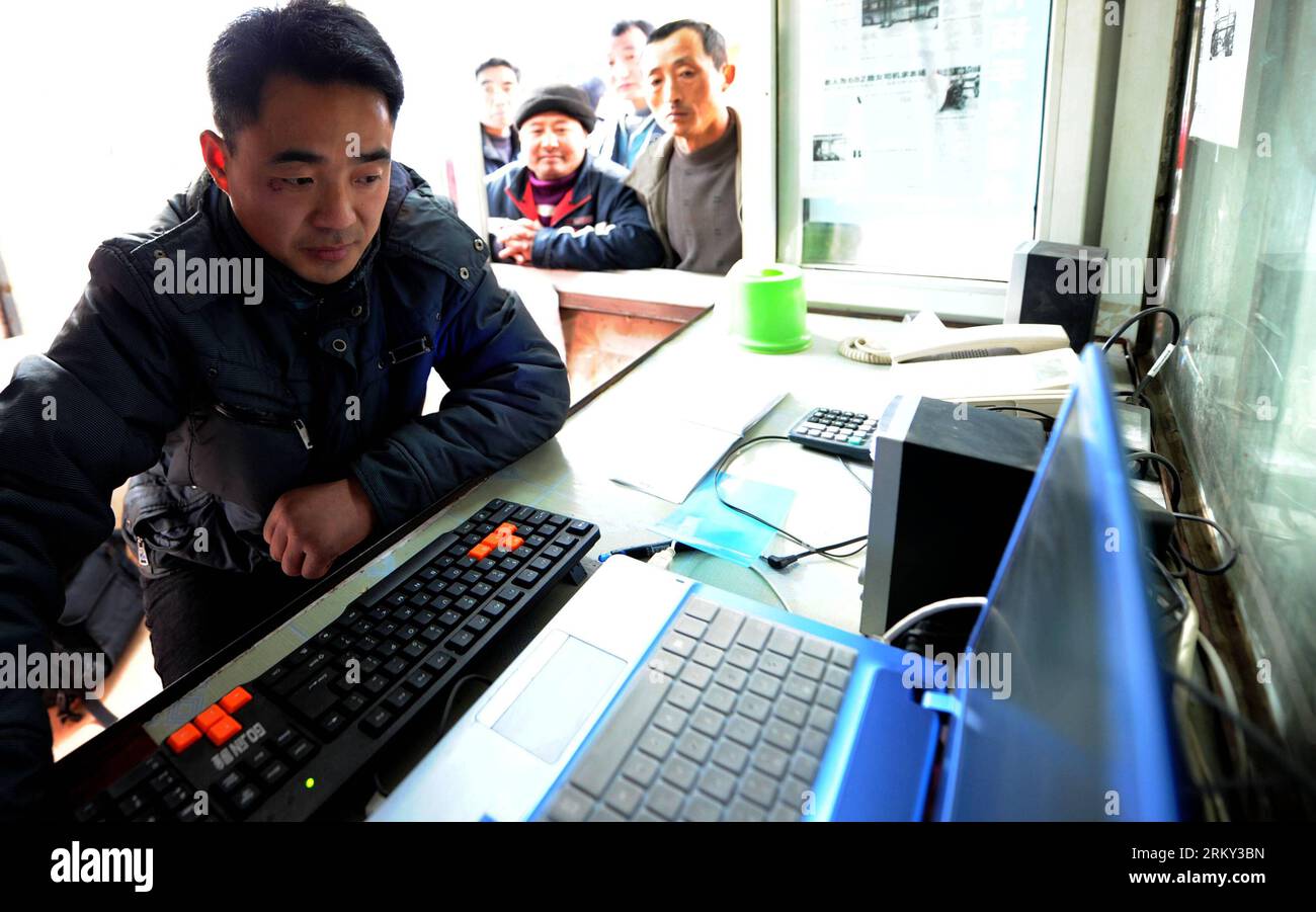 Bildnummer: 59132024  Datum: 25.01.2013  Copyright: imago/Xinhua (130125) -- HEFEI, Jan. 25, 2013 (Xinhua) -- Tao Wenzheng (front) helps migrant workers booking railway tickets at his stall in Hefei, capital of east China s Anhui Province, Jan. 25, 2013. Tao Wenzheng, 38, is a vendor who sales fried chestnuts, a kind of traditional snacks, in Hefei. He used to spent more than 10 years in Beijing as a migrant worker. After the railway authorities carried out the Internet ticket booking system, he realized that many migrant works do not know how to use the Internet, let along buying tickets onli Stock Photo