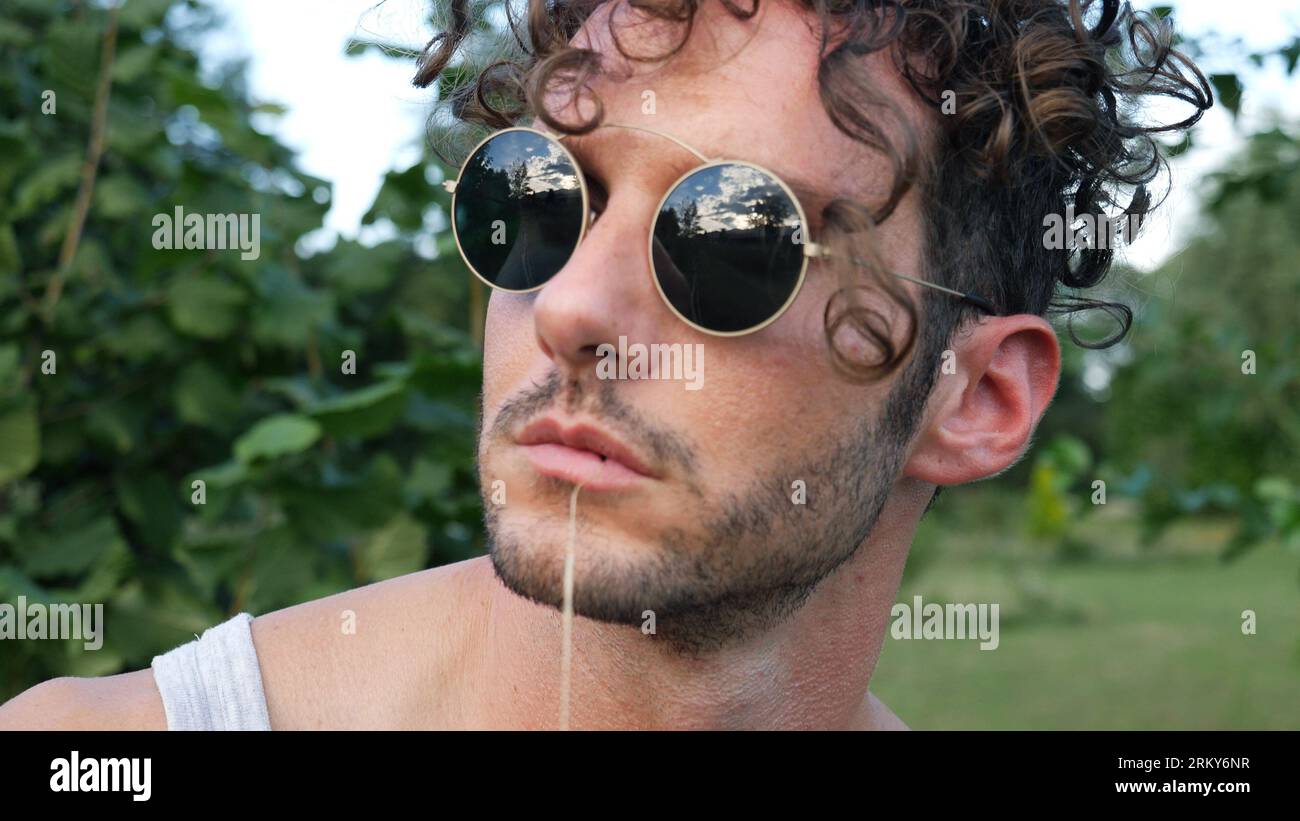 Photo of a stylish man with curly hair and round sunglasses Stock Photo ...