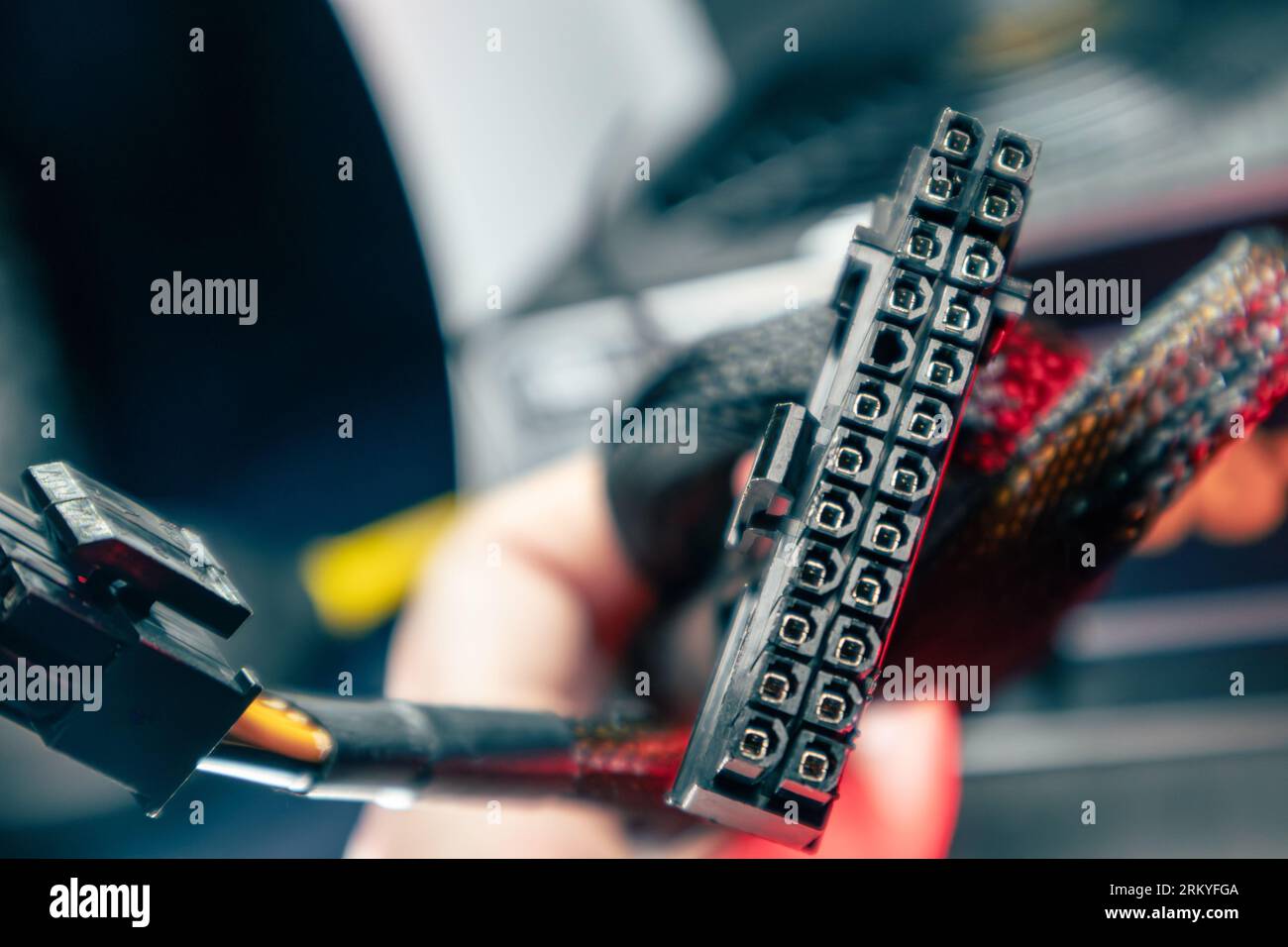 Cable connector (24 pin) from power supply unit of desktop PC close-up with blurred background. Computer wires hardware components Stock Photo