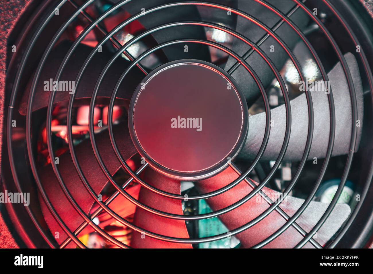 Black cooler fan with metal mesh, PC hardware details. Desktop PC CPU unit cooling radiator close-up in red light. Components from powerful modern per Stock Photo