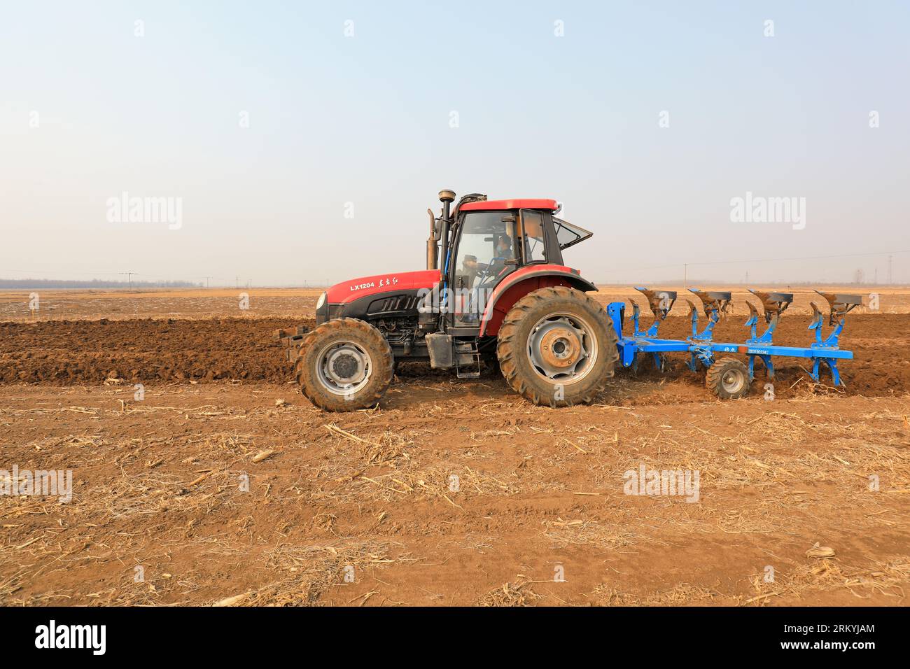 Farmers flatten their land with turning ploughs for spring ploughing
