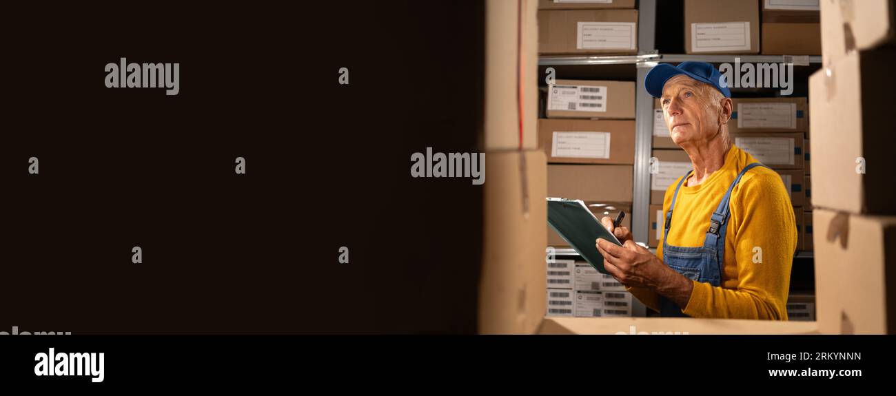 Storeroom Manager Elderly male inventory manager checks stock, writing notes in the ...