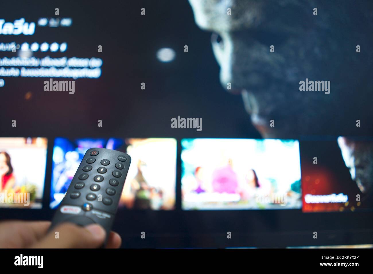 Hand with TV remote control, switching TV series from streaming service platform. The new way of enjoying entertainment at home. Stock Photo