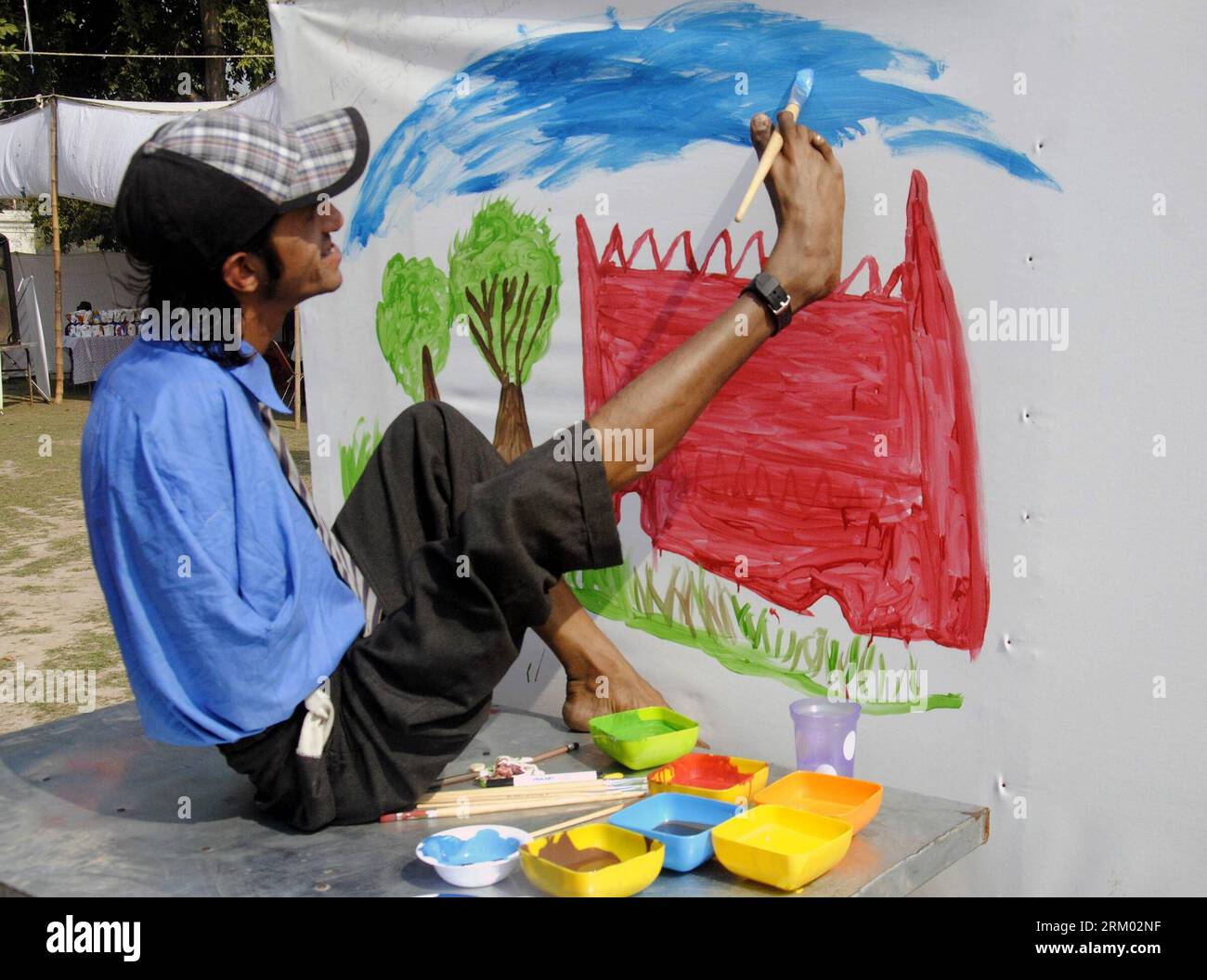 130306 -- LAHORE, March 6, 2013 Xinhua -- A handicapped Pakistani artist uses his foot to paint a wall along a street in eastern Pakistan s Lahore, March 6, 2013. More than 200 art students and youths participated in a street art painting competition run by a local youth organization with the aim of improving the city vista. Xinhua/Sajjad PAKISTAN-LAHORE-STREET PAINTING-CONTEST PUBLICATIONxNOTxINxCHN Stock Photo