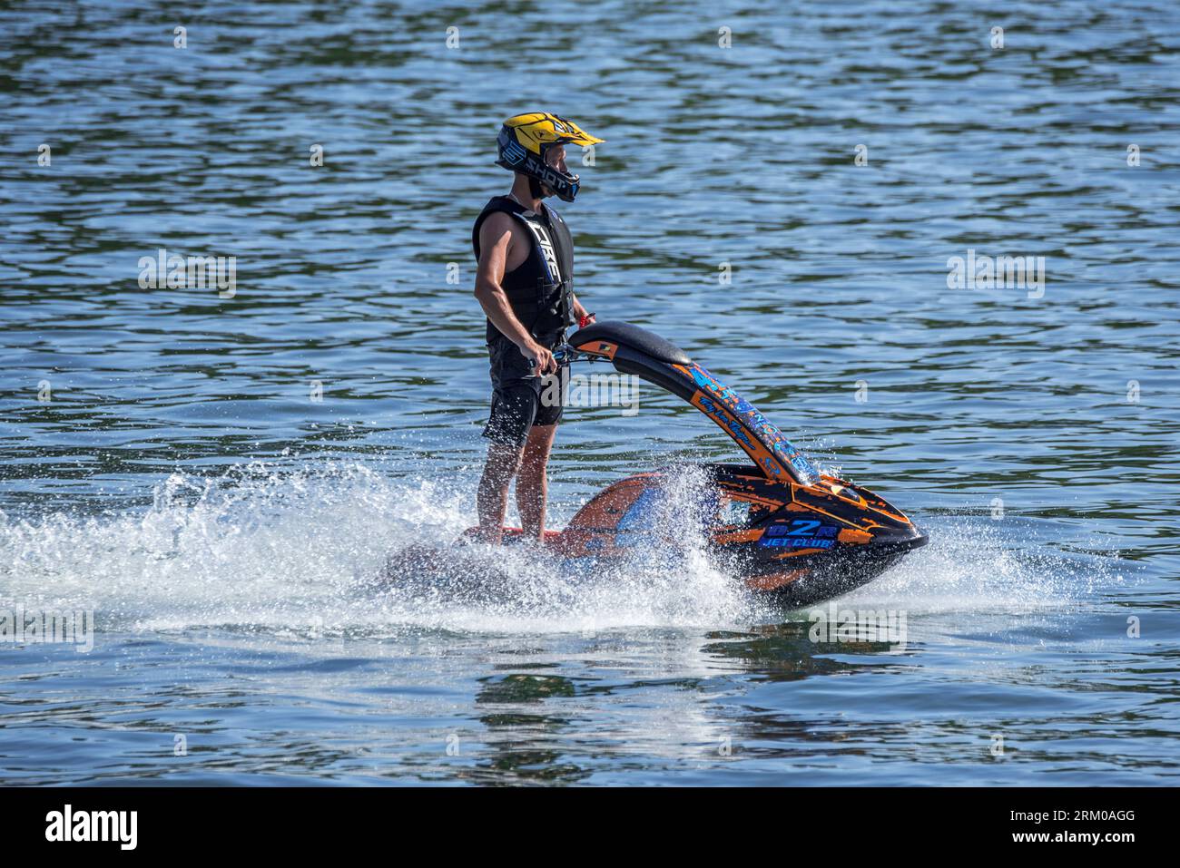 Jet skier riding jet ski / jetski / water scooter / stand-up personal watercraft / PWC on lake Stock Photo