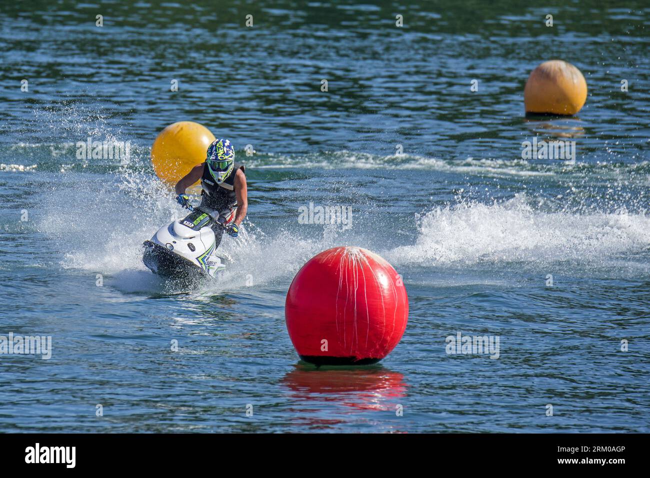 Jet ski / jetski / water scooter / stand-up personal watercraft / PWC rider slaloming along buoys on lake Stock Photo
