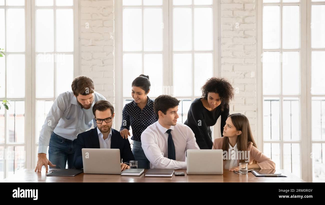 Smiling multiracial employees cooperate using laptops in office Stock Photo