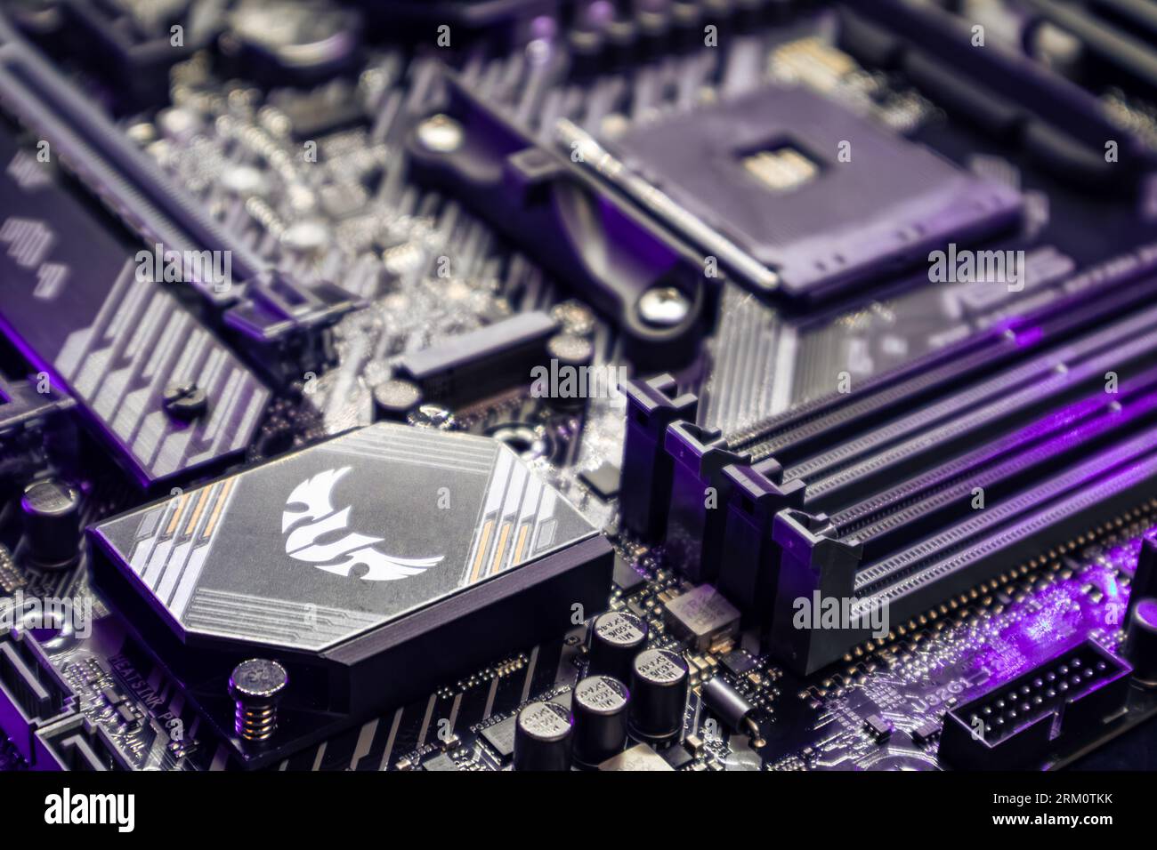 Kyiv, Ukraine - January 05, 2022: Asus Tuf Gaming modern PC motherboard with AM4 CPU Socket. Computer hardware components close-up in purple light. Te Stock Photo