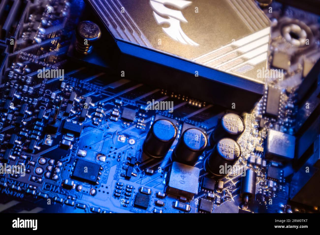 Kyiv, Ukraine - January 05, 2022: Asus Tuf Gaming modern PC motherboard with transistors and sockets. Computer chipset components close-up in blue lig Stock Photo