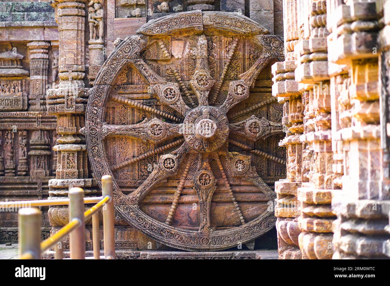 An antique sun wheel, depicting a chariot and sundial, sits in front of the Sun Temple in Konark, Odisha, India Stock Photo