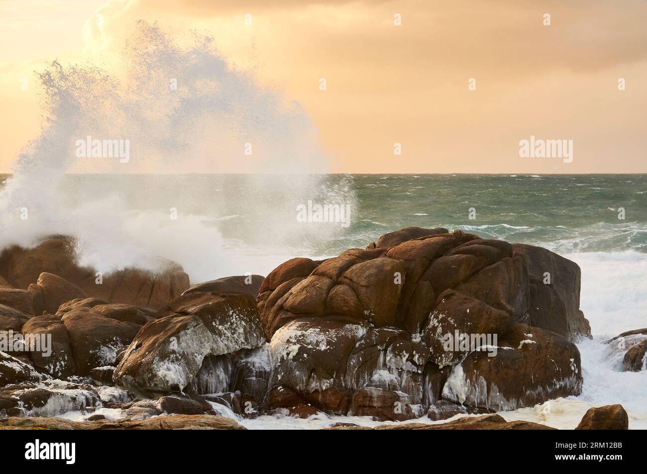 Breaking wave hitting the rocky coastline of Costa da Morte coast with rough sea at sunset (Muxía, Fisterra, A Coruña, Galicia, Atlantic Sea, Spain) Stock Photo