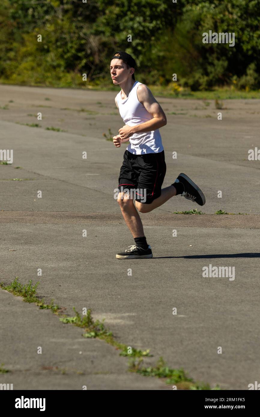 Fit and sporty teenage boy wearing a backwards cap, running outsid eon