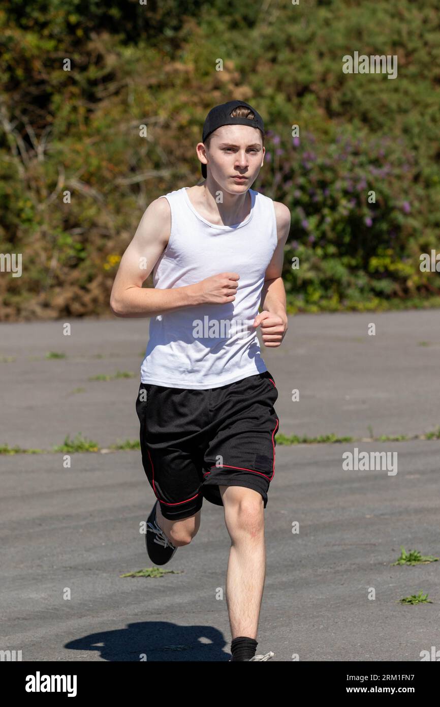 Fit and sporty teenage boy wearing a cap backwards, running during a
