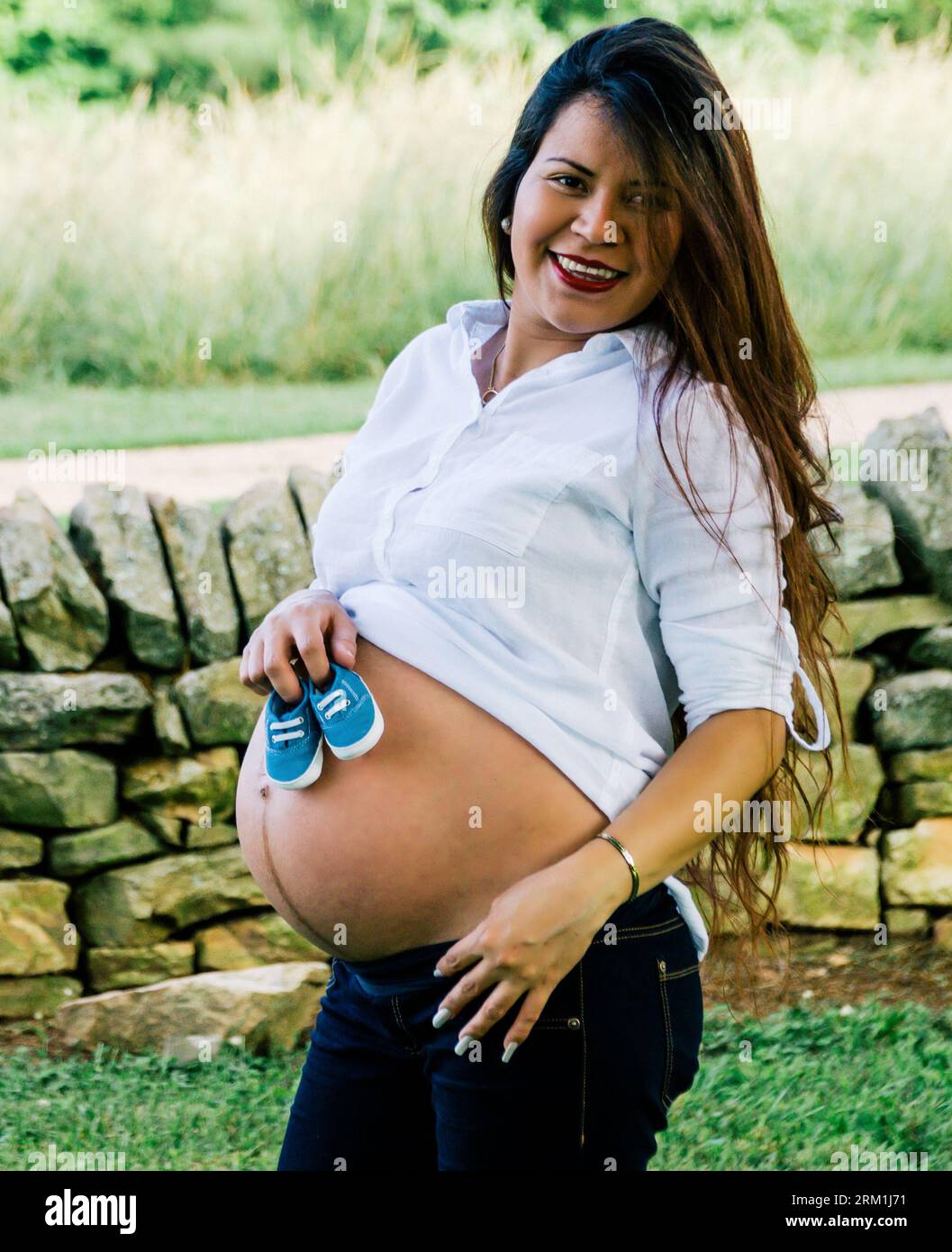 Mexican woman smiling while holding two shoes on her belly area for a