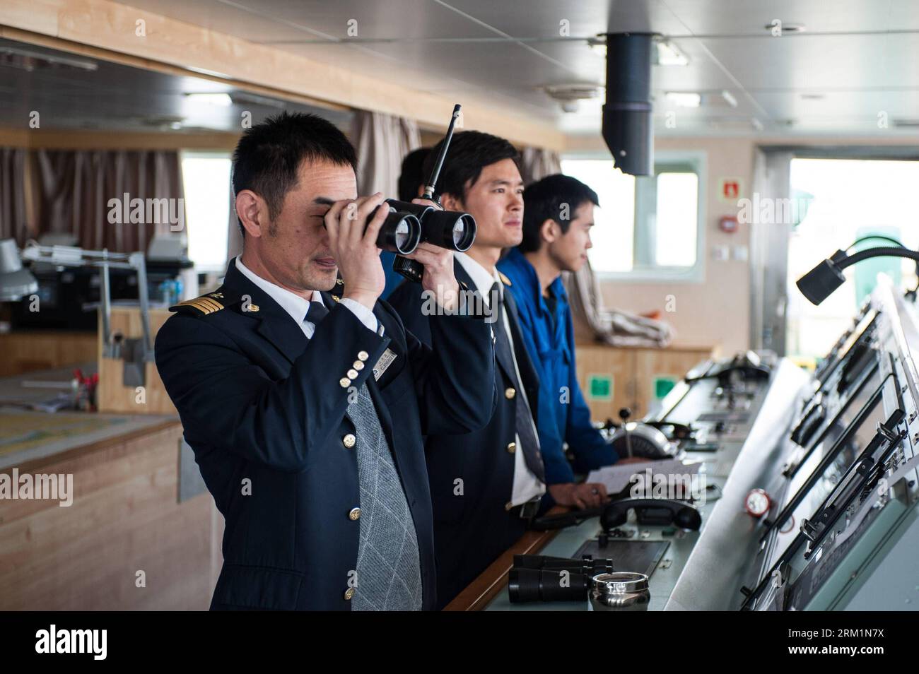 Bildnummer: 59604346  Datum: 24.04.2013  Copyright: imago/Xinhua NANJING, 2013 - Wang Lianmiao (1st L) checks sailing conditions using telescope aboard the Maple Star on the Yangtze River in east China s Jiangsu Province, April 24, 2013. Wang Lianmiao and Zhu Hui arrived at the port of Jingjiang on the morning of April 24, 2013. Both men are inland waterway pilots from the Yangtze River Pilot Centre. Awaiting them was the Maple Star, a 180-meter-long Marshall Islands-flagged cargo ship with a gross register tonnage of over 23,000. Under their pilotage, the Maple Star was to veer 180 degrees an Stock Photo
