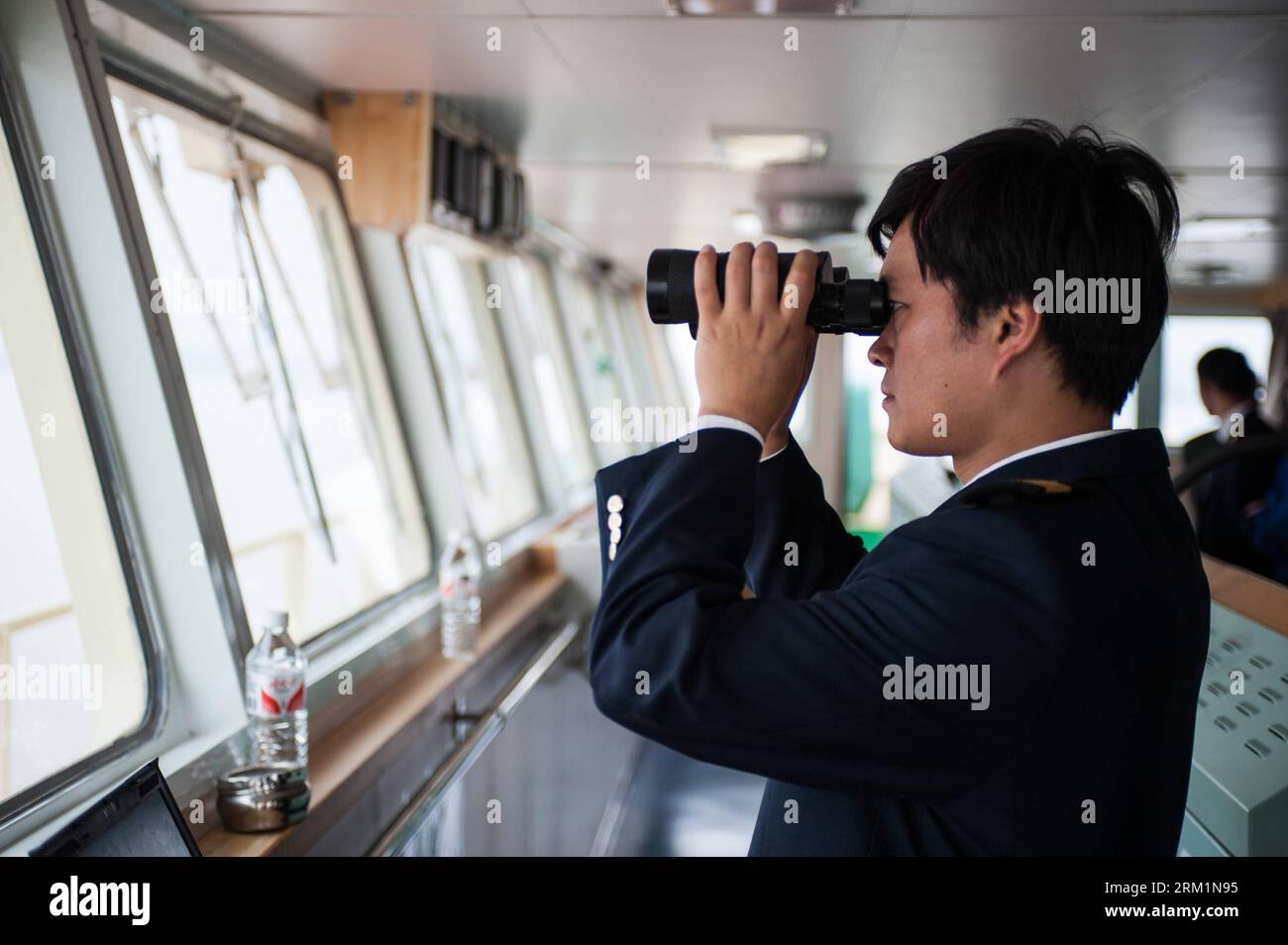 Bildnummer: 59604351  Datum: 24.04.2013  Copyright: imago/Xinhua NANJING, 2013 -- Zhu Hui checks sailing conditions using telescope aboard the Maple Star on the Yangtze River in east China s Jiangsu Province, April 24, 2013. Wang Lianmiao and Zhu Hui arrived at the port of Jingjiang on the morning of April 24, 2013. Both men are inland waterway pilots from the Yangtze River Pilot Centre. Awaiting them was the Maple Star, a 180-meter-long Marshall Islands-flagged cargo ship with a gross register tonnage of over 23,000. Under their pilotage, the Maple Star was to veer 180 degrees and head downst Stock Photo