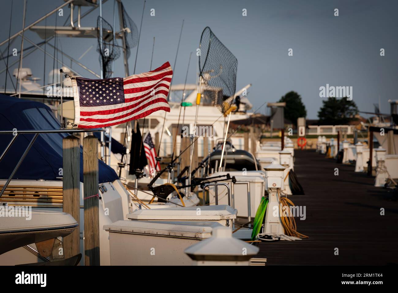 The sun rises on an American flag on the back of a boat in the harbor at Ludington, Michigan. Stock Photo