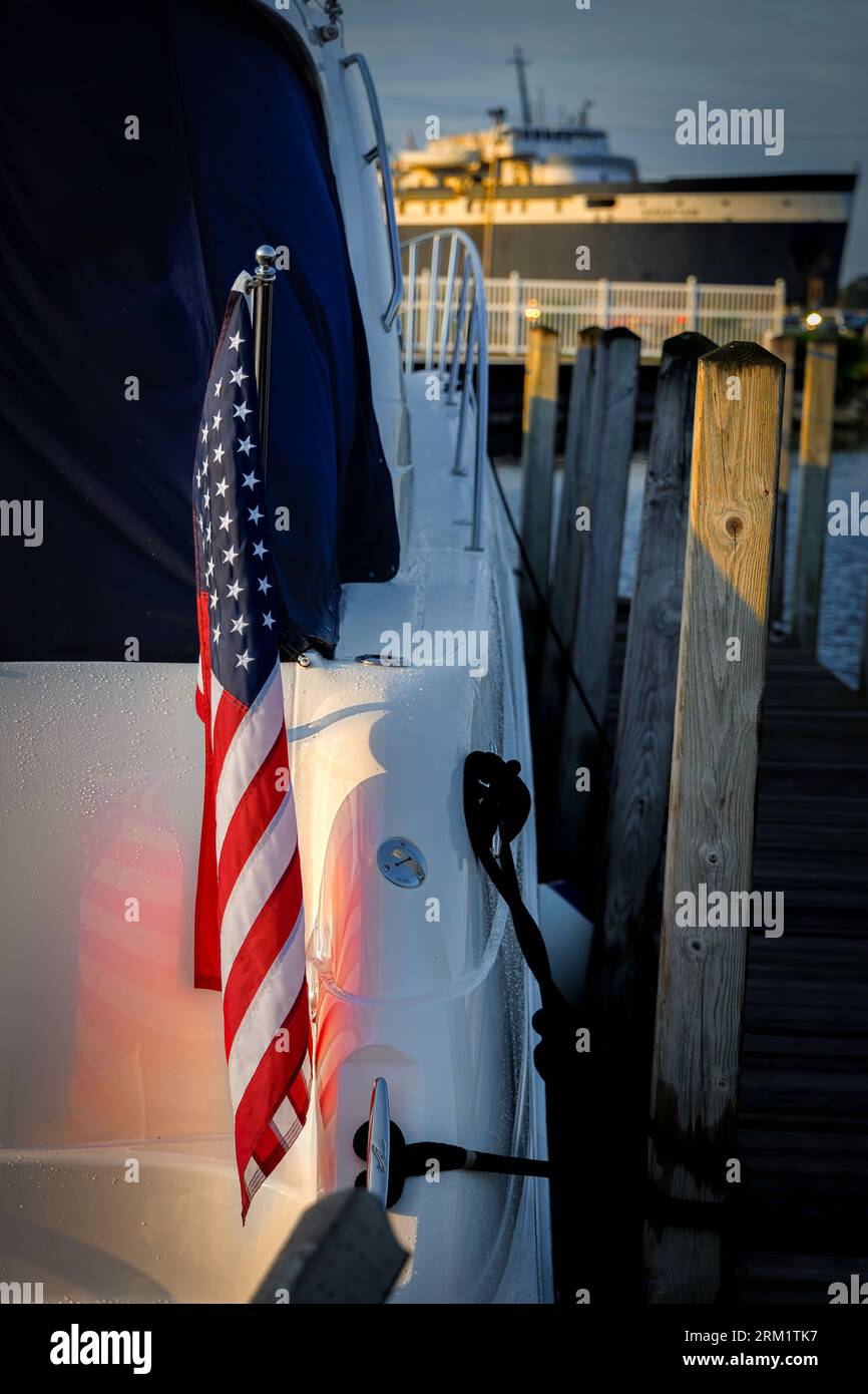 The sun rises on an American flag on the back of a boat in the harbor at Ludington, Michigan. Stock Photo