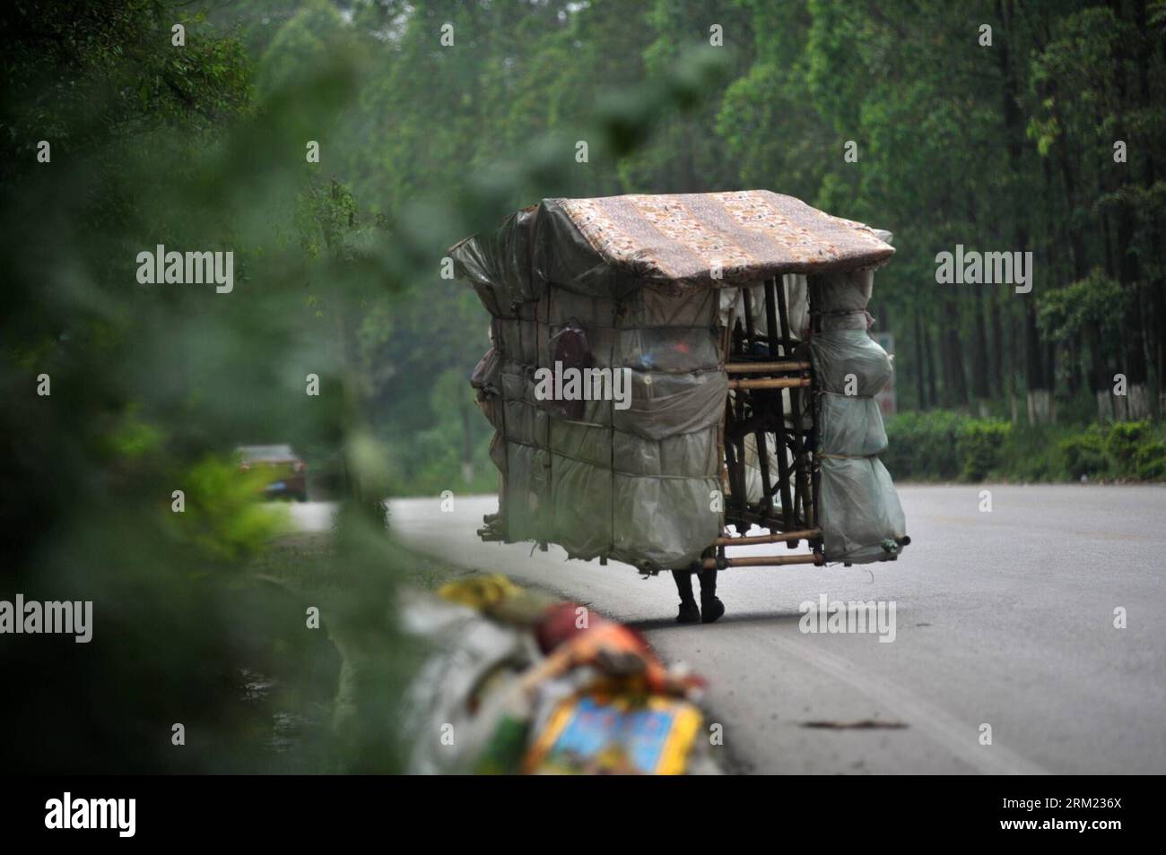 Bildnummer: 59677575  Datum: 21.05.2013  Copyright: imago/Xinhua LIUZHOU -- Liu Lingchao carries his moving hut on a road in Liucheng County of Liuzhou City, south China s Guangxi Zhuang Autonomous Region, May 21, 2013. Liu, a 38-year-old migrant worker from Liuzhou s Rong an County, decided to make a moving hut five years ago in Guangdong Province to live in on his way to Rong an, his hometown. The hut measures about 60 kilograms in weight, 1.5 meters in length and 2.2 meters in height. Since then, Liu has been carrying a hut and making a living by collecting rubbishes along the way. Having w Stock Photo
