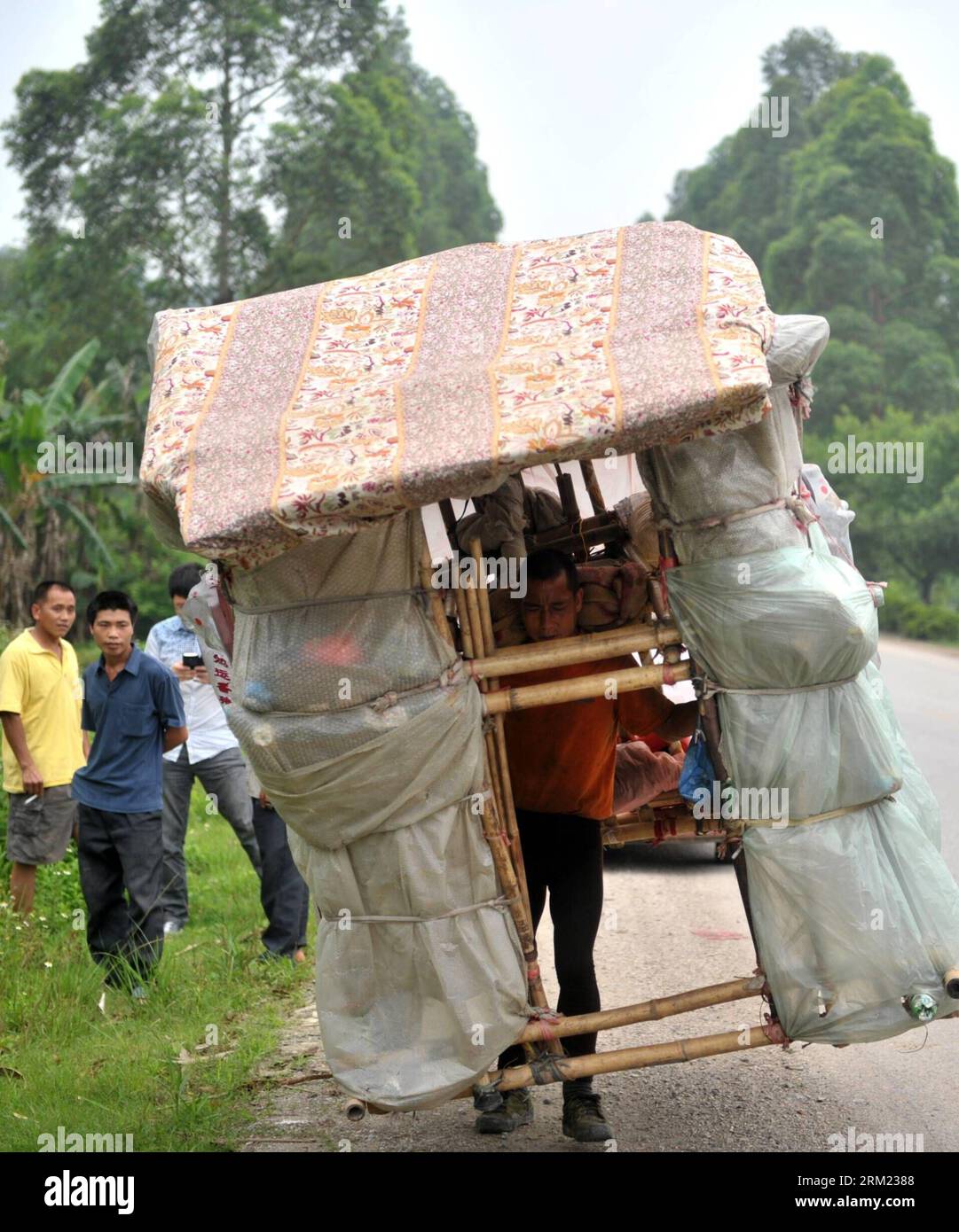 Bildnummer: 59677573  Datum: 21.05.2013  Copyright: imago/Xinhua LIUZHOU -- Liu Lingchao carries his moving hut on a road in Liucheng County of Liuzhou City, south China s Guangxi Zhuang Autonomous Region, May 21, 2013. Liu, a 38-year-old migrant worker from Liuzhou s Rong an County, decided to make a moving hut five years ago in Guangdong Province to live in on his way to Rong an, his hometown. The hut measures about 60 kilograms in weight, 1.5 meters in length and 2.2 meters in height. Since then, Liu has been carrying a hut and making a living by collecting rubbishes along the way. Having w Stock Photo