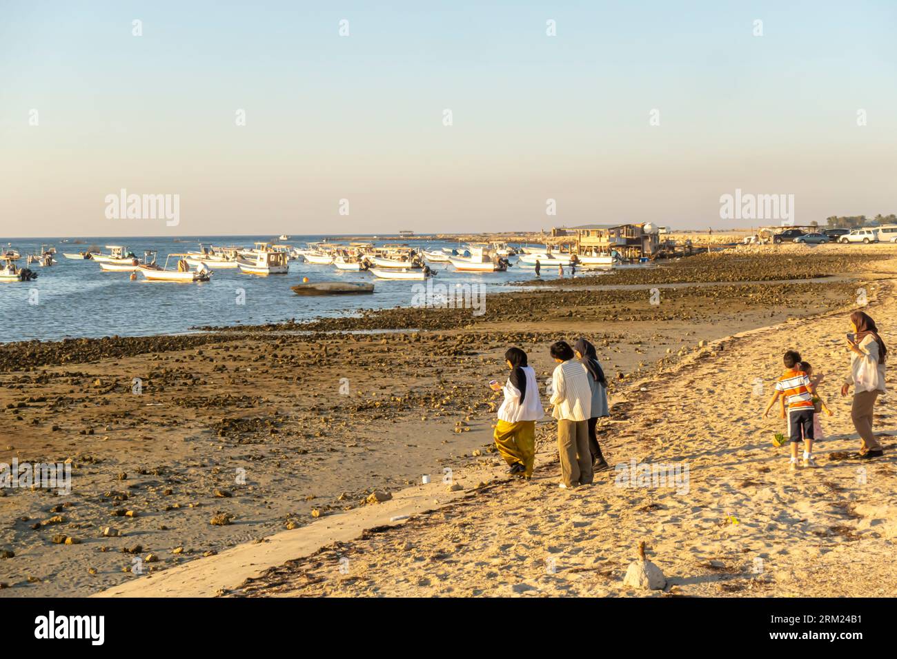 Scenic view of Persian Gulf shore, family coming to the boats moored at Karbabad beach, Seef beach Bahrain, Middle East Stock Photo