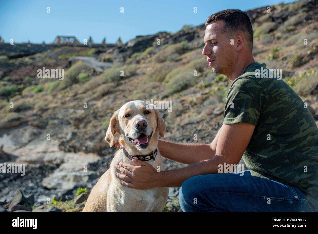 Caucasian dog trainer cuddles labrador dog after successful work session Stock Photo