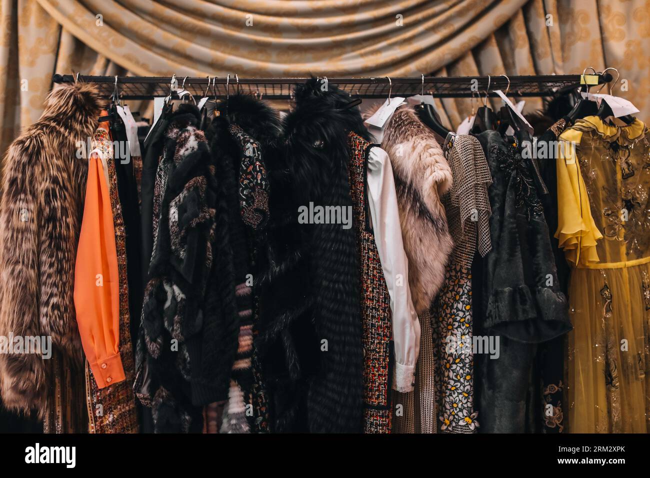 Women's evening long dresses and fur coats hanging on hangers on the  fashion backstage in the vintage interior Stock Photo - Alamy