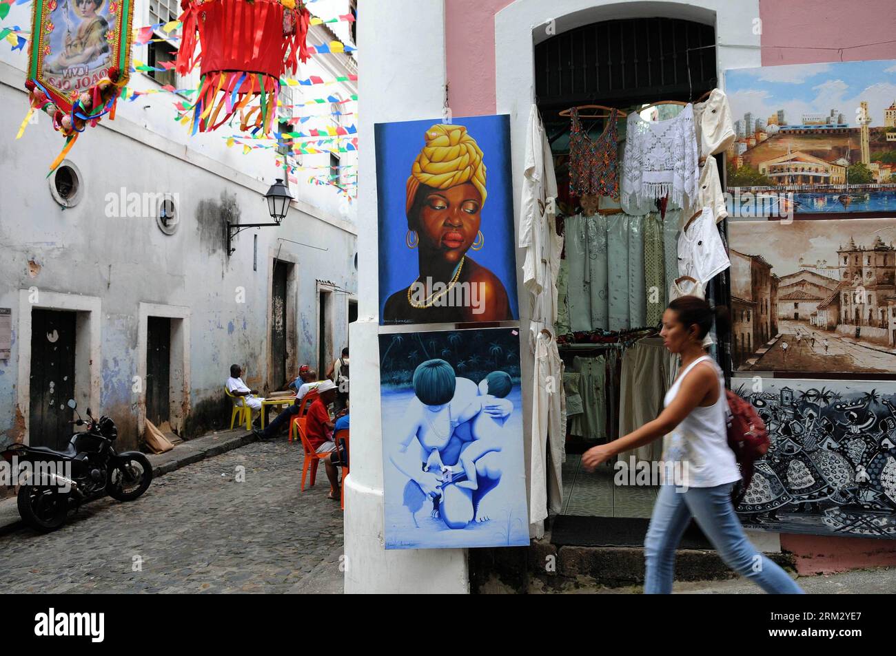 Bildnummer: 59917547  Datum: 28.06.2013  Copyright: imago/Xinhua BAHIA, June 28, 2013 - A woman walks in front of pictures and clothes on a street in the neighborhood of Pelourinho, in Salvador de Bahia, Bahia state, Brazil, on June 28, 2013. The neighborhood of Pelourinho is located in the historical center of Salvador de Bahia and part of the historical heritage of the UNESCO. Bahia will be the venue of third and fourth place match of the FIFA s Confederations Cup Brazil 2013. (Xinhua/Nicolas Celaya) (itm) (SP)BRAZIL-BAHIA-CONFEDERATIONS-DAILY LIFE PUBLICATIONxNOTxINxCHN xas x0x 2013 quer Stock Photo