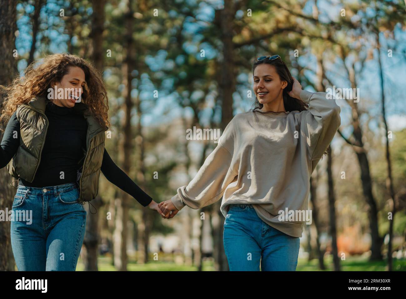 Front view shot of two girls hanging out in the park. They are having ...