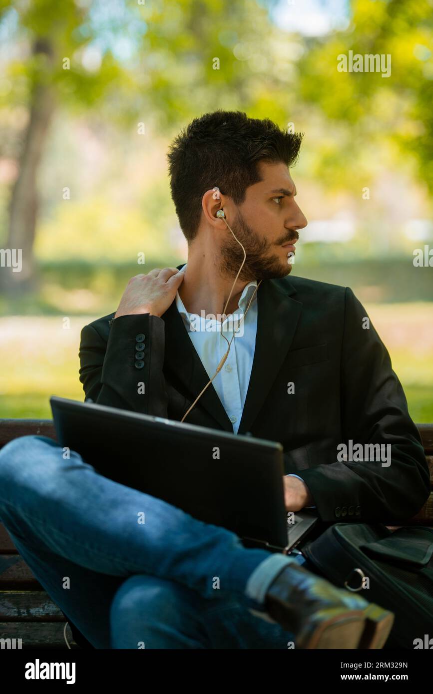 Businessman sitting on the bench with his laptop and headphones Stock ...