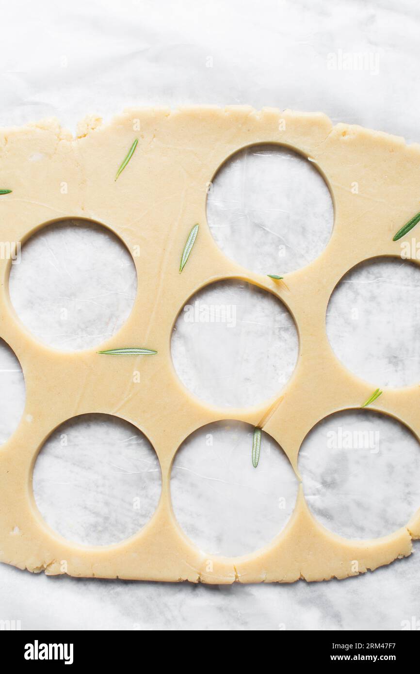 Top view of cutting out rosemary sugar cookie dough, herb cookie dough