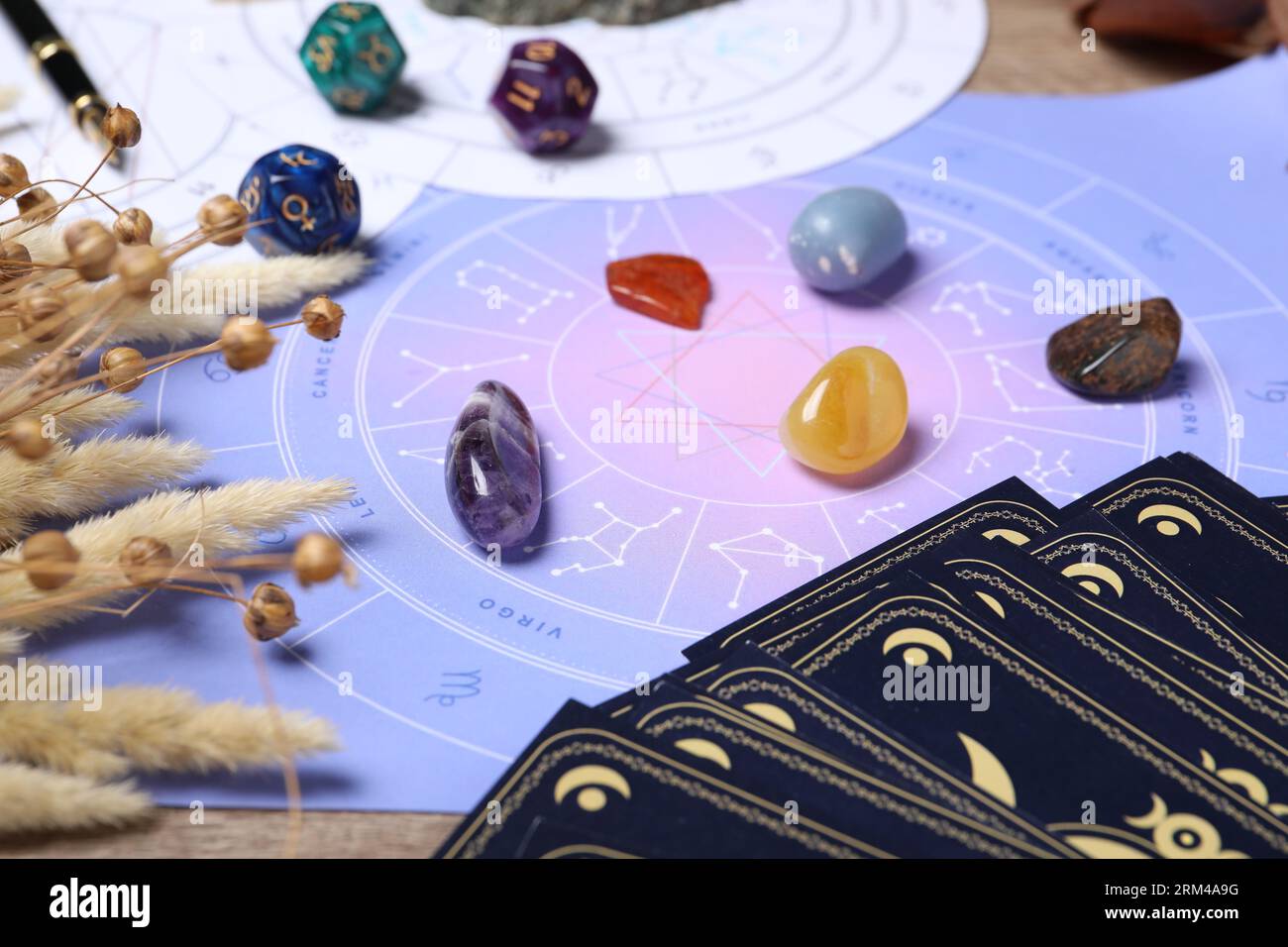 Zodiac wheel, tarot cards, astrology dices and gemstones on table