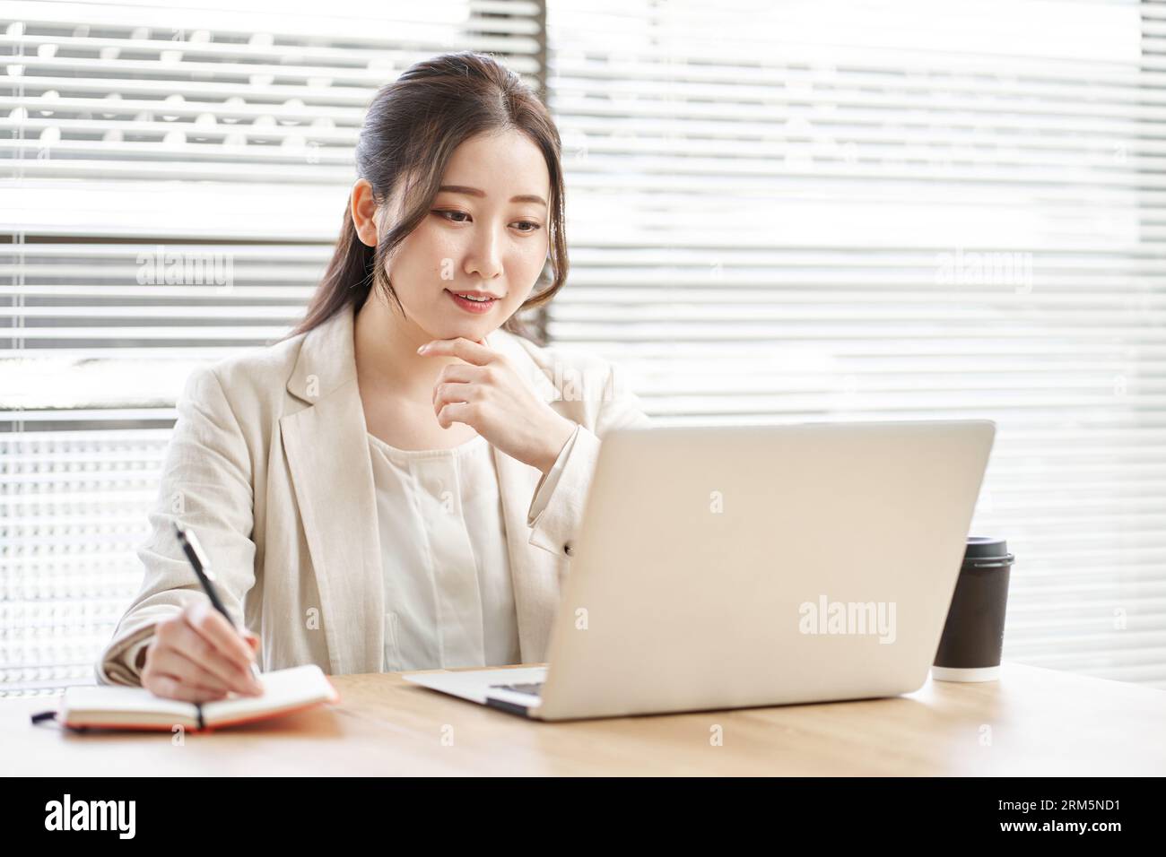 Asian woman taking notes in a coworking space Stock Photo