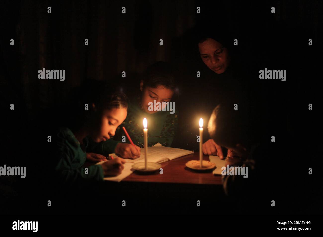 Bildnummer: 60746194  Datum: 22.11.2013  Copyright: imago/Xinhua     Palestinians refugee kids study with their mother at their house during the electricity outage in Al Shatea refugee camp in the west of Gaza city, on Nov. 22, 2013. (Xinhua/Wissam Nassar) (jl) MIDEAST-GAZA-ELECTRICITY PUBLICATIONxNOTxINxCHN Gesellschaft xdp x2x 2013 quer premiumd o0 Land leute kerze kerzenschein stromausfall strom ausfall dunkel familie kinder hausaufgaben schule bildung Stock Photo