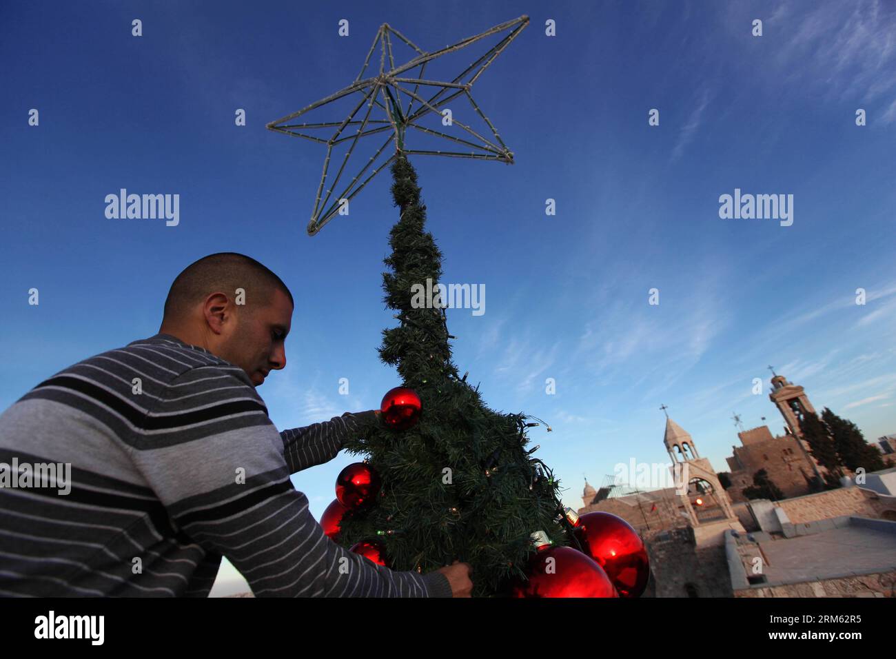 Bildnummer: 60775424  Datum: 30.11.2013  Copyright: imago/Xinhua     A worker puts final touches on a huge Christmas tree erected near the Church of the Nativity in the West Bank city of Bethlehem on Nov. 30, 2013. (Xinhua/Luay Sababa) MIDEAST-BETHLEHEM-CHRISTMAS TREE PUBLICATIONxNOTxINxCHN xcb x0x 2013 quer Stock Photo