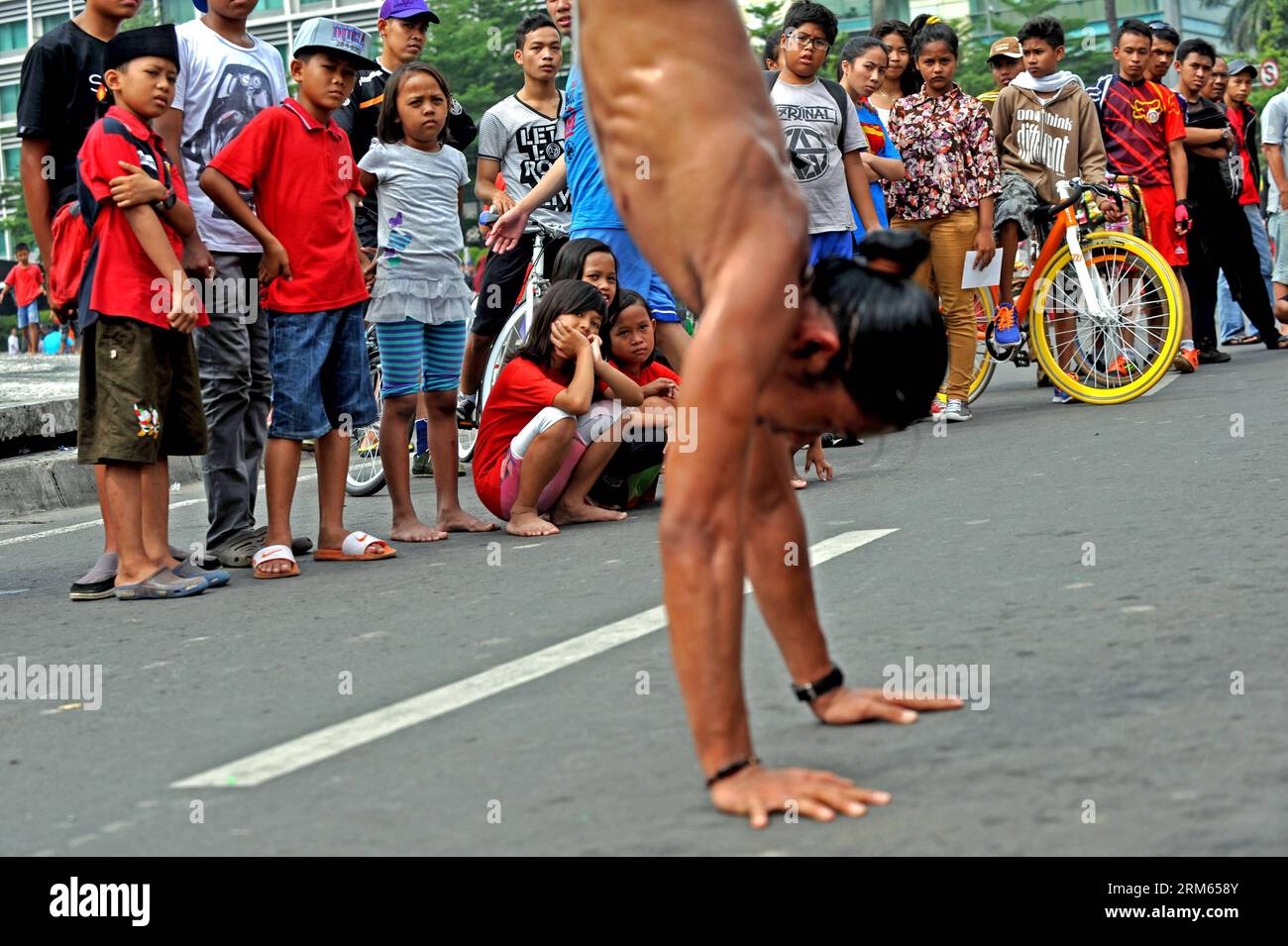 Bildnummer: 60806603  Datum: 08.12.2013  Copyright: imago/Xinhua     Children watch a man from Indonesian Jumper community do handstand of parkour and free run during the car free day in Jakarta, Indonesia, Dec. 8, 2013. (Xinhua/Agung Kuncahya B.) INDONESIA-JAKARTA-CAR FREE DAY PUBLICATIONxNOTxINxCHN xcb x0x 2013 quer Stock Photo